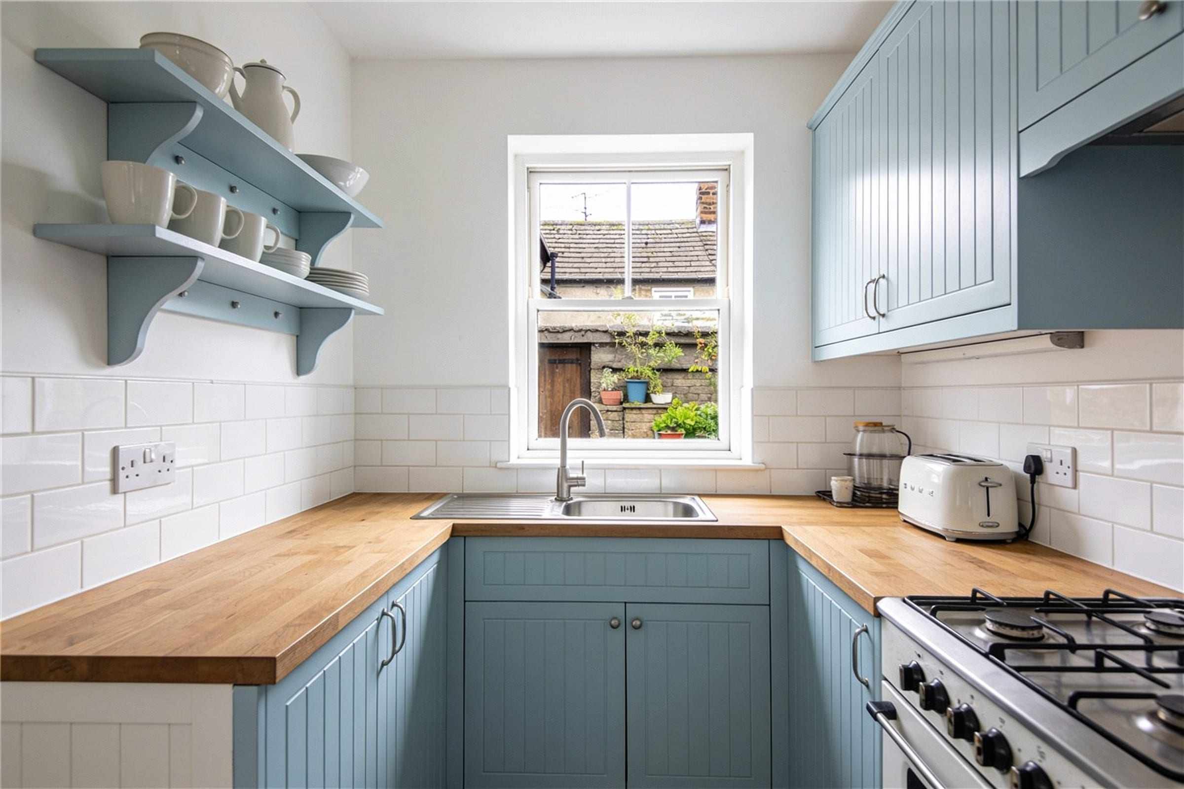 The kitchen with pale blue cabinets and a window onto the courtyard.
