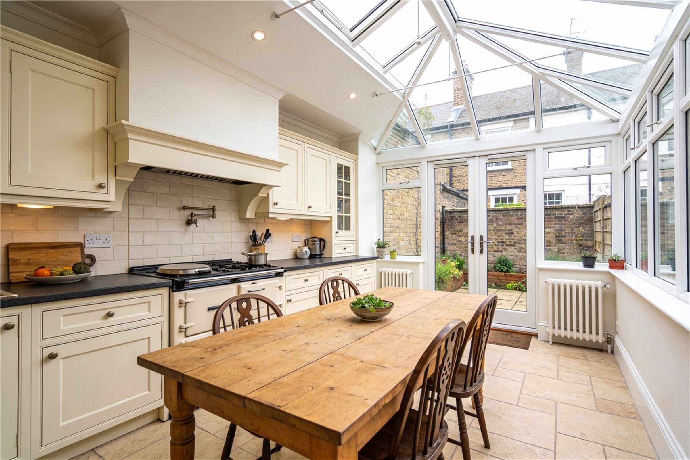 The kitchen extension with a glass roof, a long table and doors to the walled garden.