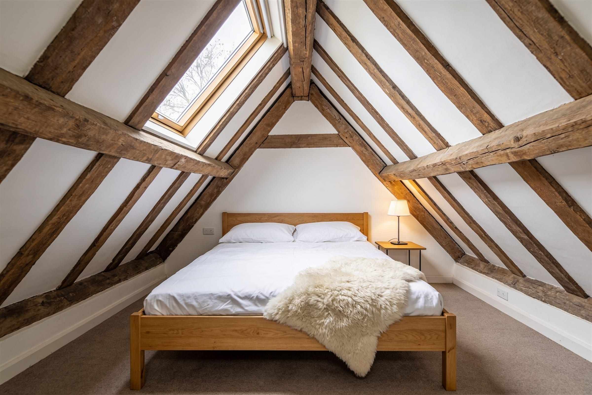 The bedroom under sloping rafters with a roof window.