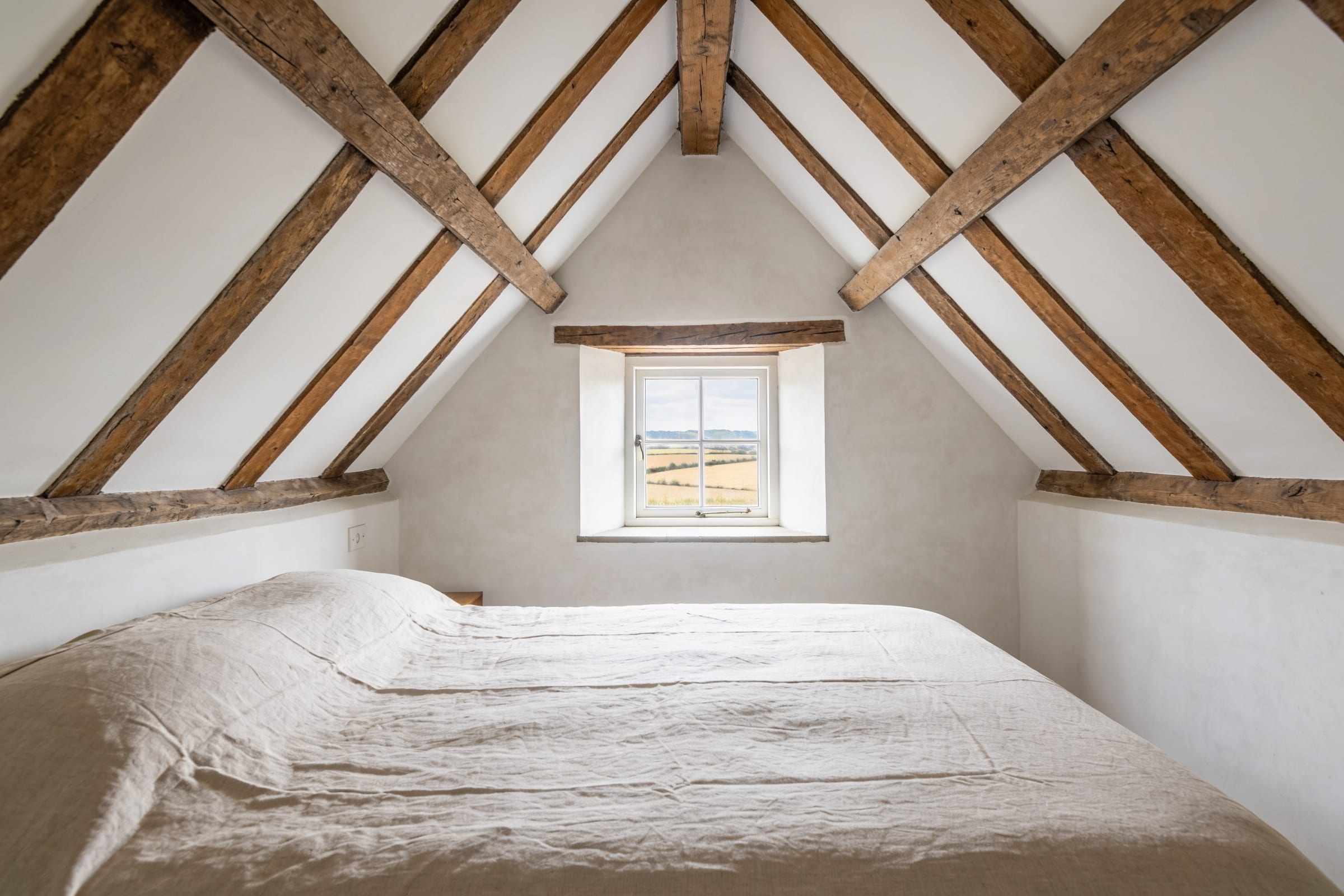 The main bedroom under a vaulted ceiling with oak trusses.